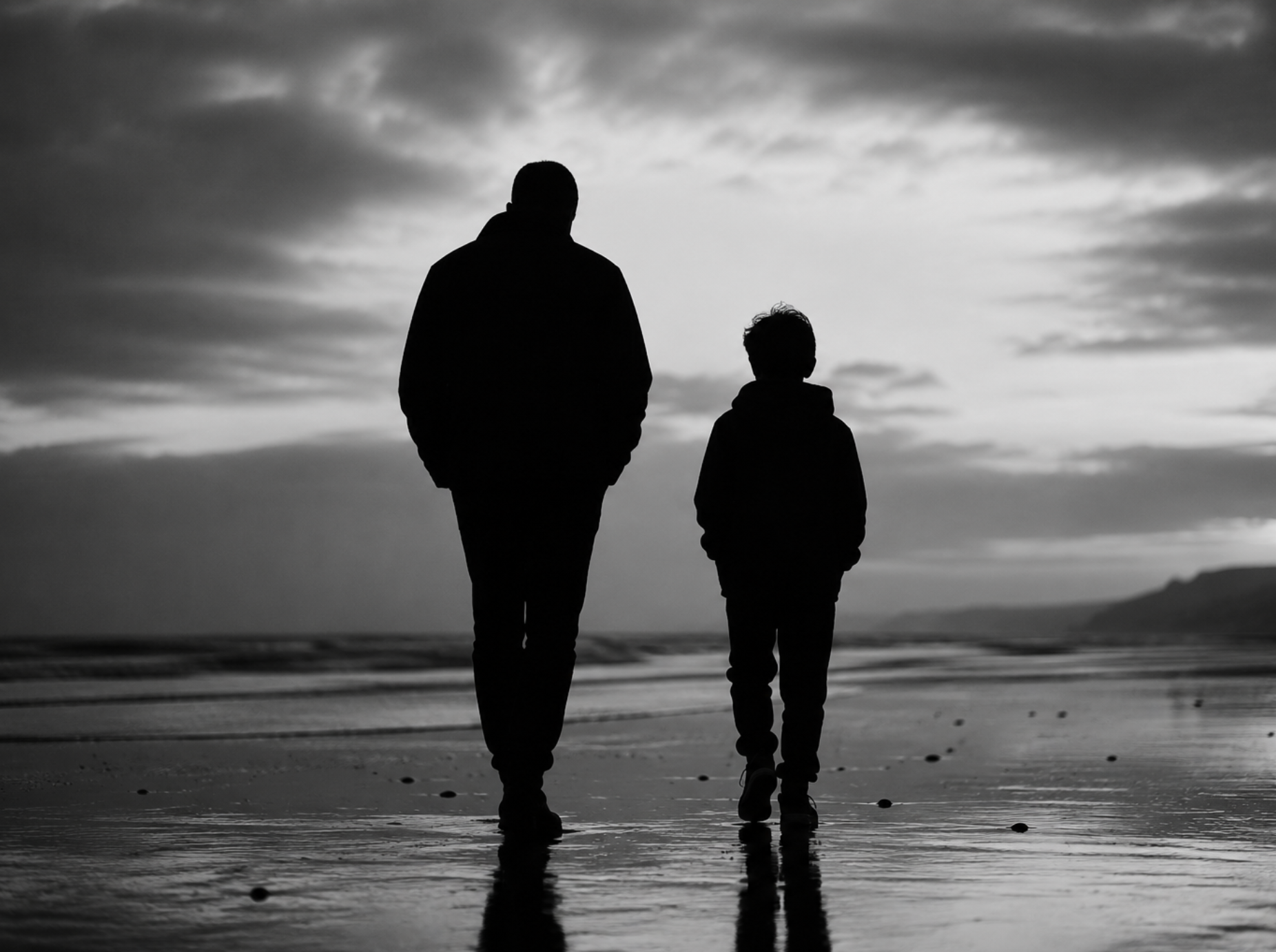 Father and son walking together on a beach at dusk